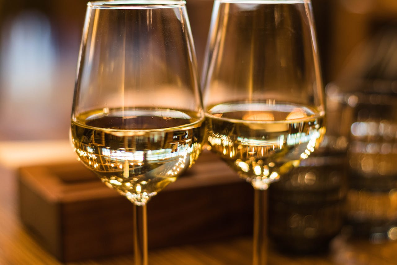 about-02 Two elegant wine glasses filled with white wine, captured with a beautiful bokeh effect.